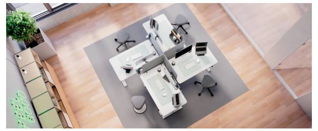 Draufsicht auf einen modernen Büroarbeitsplatz mit vier Schreibtischen, die um eine zentrale Stützstruktur angeordnet sind, mehreren Drehstühlen und einer Topfpflanze in der Nähe.