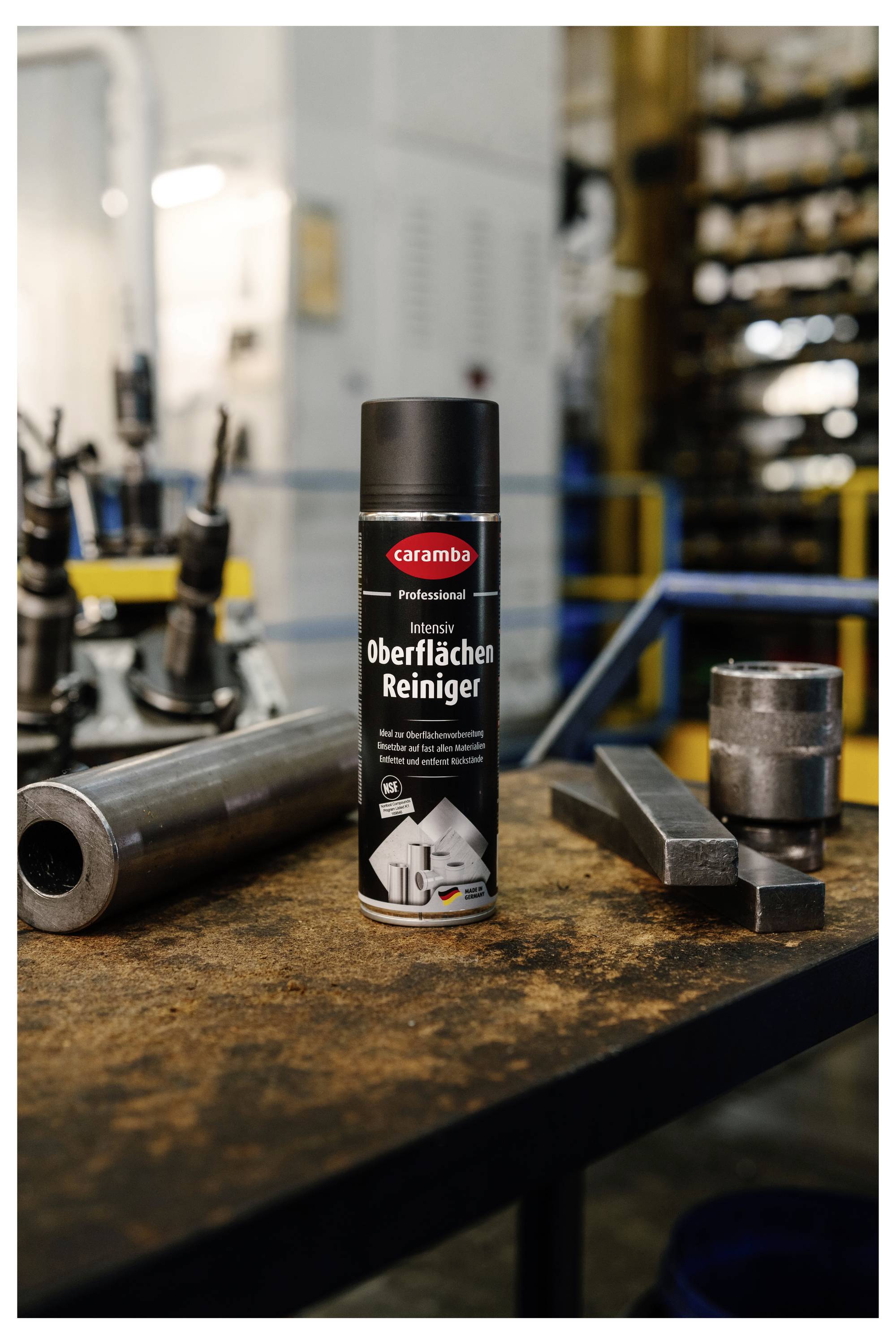Eine Dose Caramba Professional Intensiver Oberflächenreiniger steht auf einer Werkstattwerkbank neben Metallteilen und Werkzeugen.