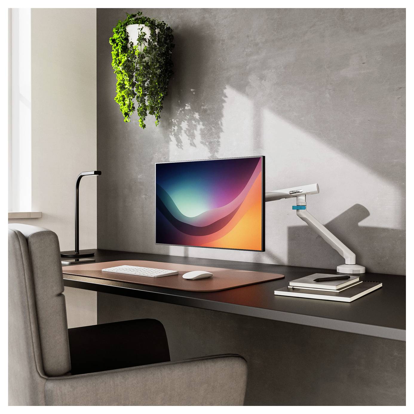 Moderner Homeoffice-Schreibtisch mit Computermonitor, Tastatur, Maus, Schreibtischlampe, Büchern und einer hängenden Pflanze neben einem grauen Stuhl am Fenster.