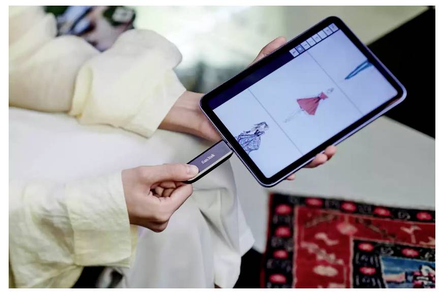 Eine Person hält ein Tablet, auf dem Kleidungsdesigns angezeigt werden, während sie eine Karte verwendet, um ein Modeprodukt zu scannen oder auszuwählen, was auf virtuelles Einkaufen oder Styling hindeutet.
