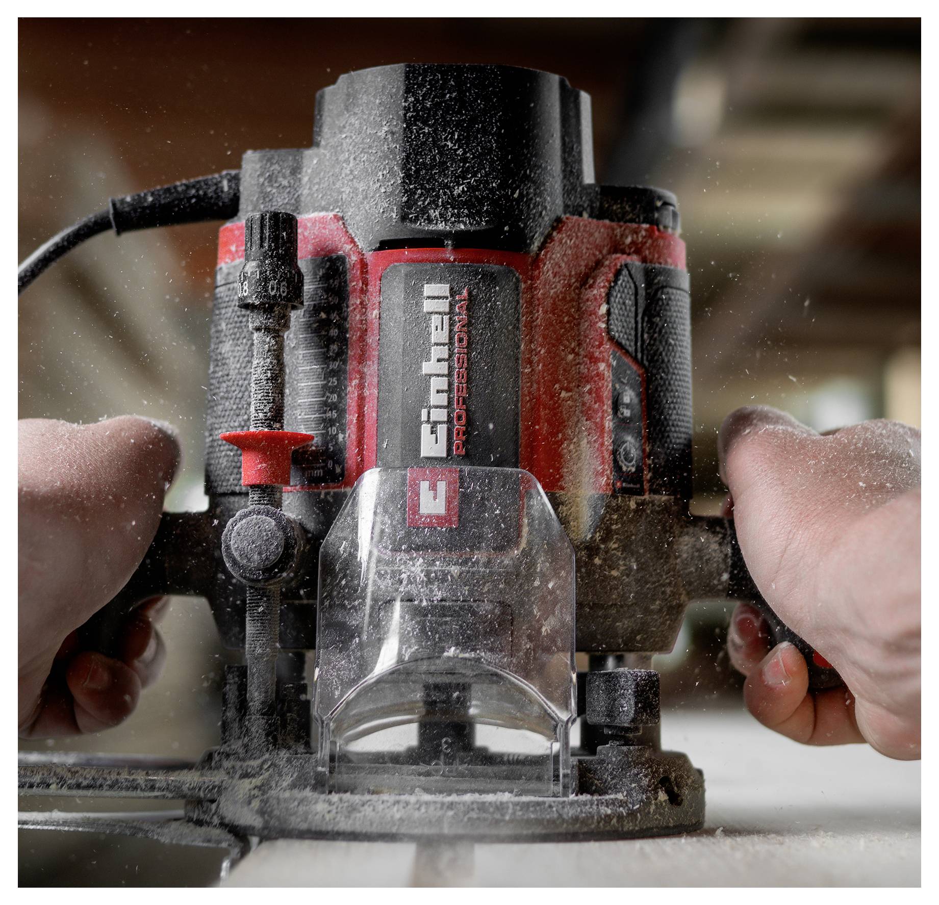 Nahaufnahme einer Person, die einen rot-schwarzen CRAFTSMAN Pro-Grade-Router verwendet, mit Staub, der fliegt, während dieser Holz schneidet.