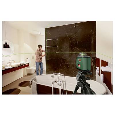 Mann stellt ein grünes Laser-Nivellier-Stativ im Badezimmer auf, um ein großes Wandpaneel über einer Badewanne auszurichten.