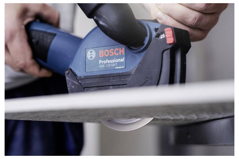 Hände, die ein Bosch Professional Elektrowerkzeug zum Zuschneiden von Material verwenden, mit einer Kreissägeblatt in Nahaufnahme sichtbar.