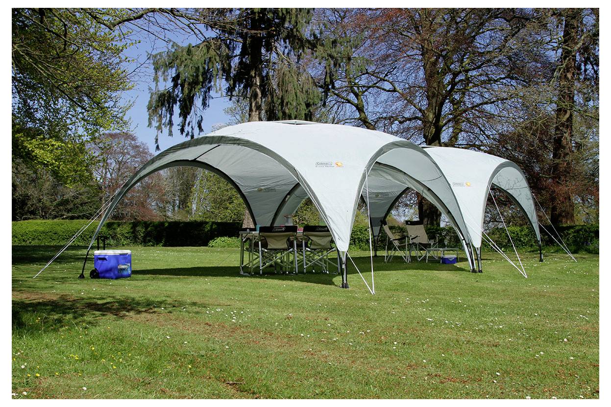 Zwei weiße Pavillon-Zelte auf einem Rasenplatz in einem Park aufgestellt, mit Klapptischen darunter und Bäumen im Hintergrund.