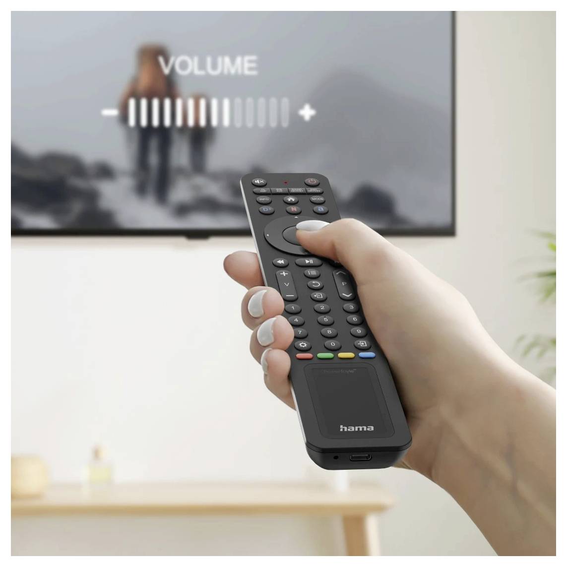 Hand hält eine Fernbedienung, während die Lautstärke auf dem Bildschirm angepasst wird, mit einem unscharfen Fernseher, der "LAUTSTÄRKE" und einen Lautstärkeregler anzeigt.