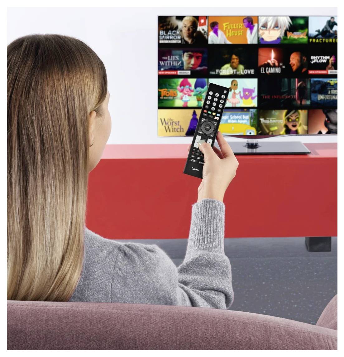 Frau, die eine Fernbedienung hält und ein Streaming-TV-Menü mit Reihen von Film- und Sendungs-Thumbnails anschaut.
