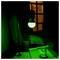 Grüner Schreibtisch mit hängender Lampe, kleine Topfpflanze und Bücher oder Papiere neben einem Fenster in der Nacht.