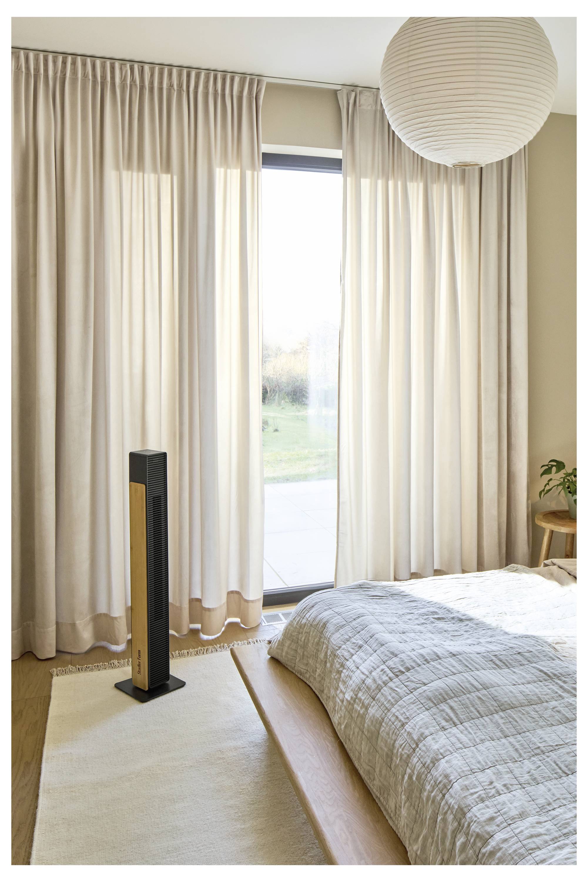 Helles Schlafzimmer mit raumhohen Vorhängen, großem Fenster, Bett, Teppich, Stehleuchte und runder Papierhängeleuchte.