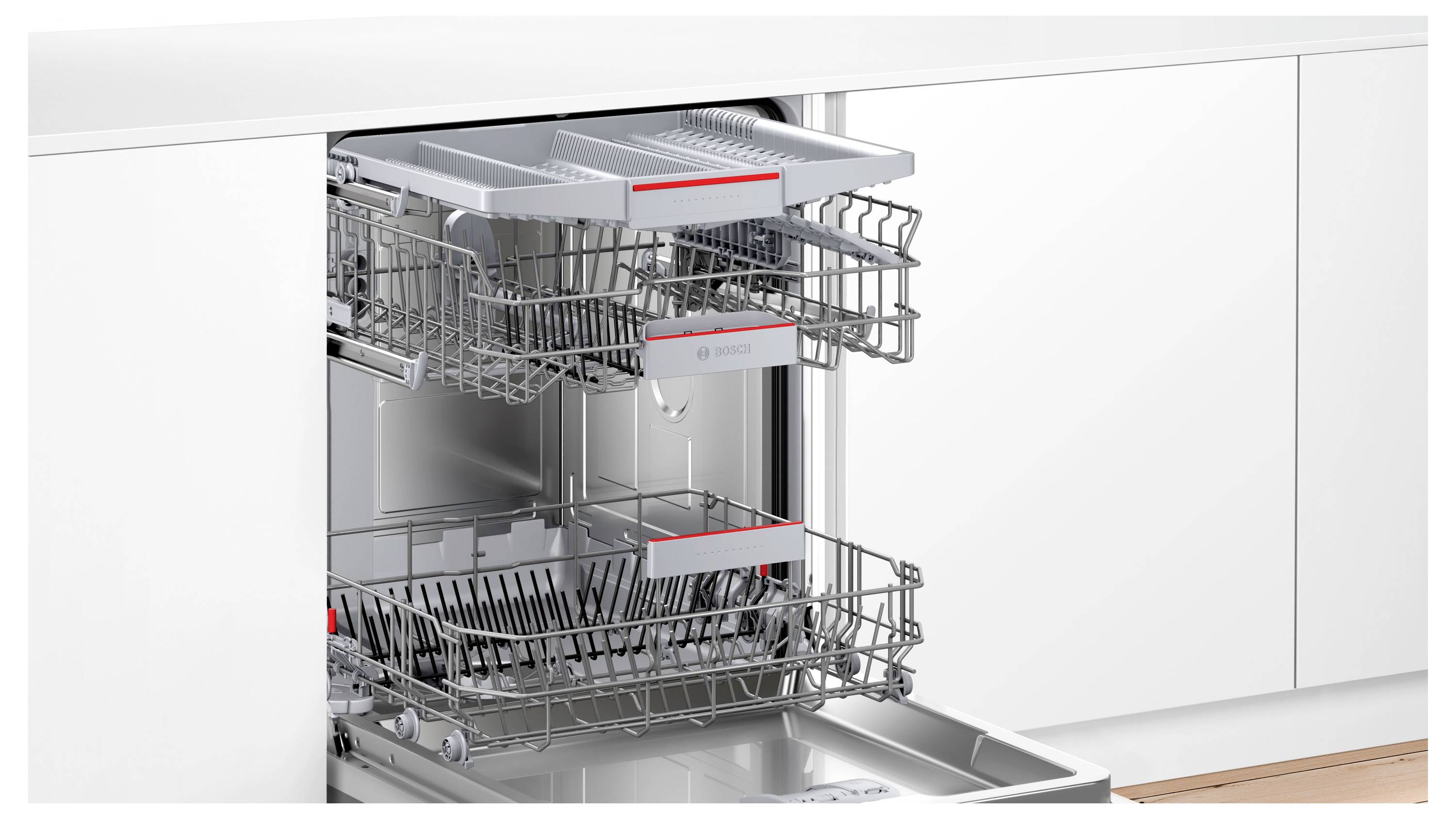 Eingebaute Spülmaschine mit ausgezogenen Ober- und Unterkörben, die leere Drahtkörbchen in einem Edelstahlschrank zeigen.