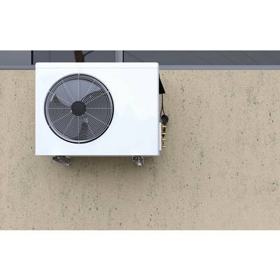 Außen angebrachte Klimaanlage mit großem kreisförmigem Lüfter an einer beigen Außenwand.