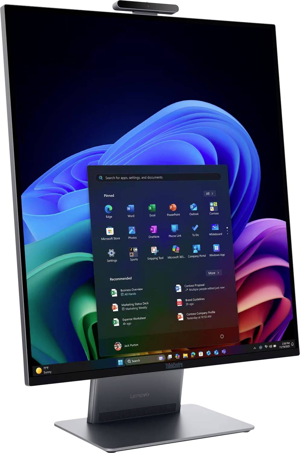 Monitor auf dem Schreibtisch, der ein Windows 11-Startmenü über der blauvioletten Standardhintergrund anzeigt, mit App-Symbolen und einer Taskleiste auf dem Bildschirm.