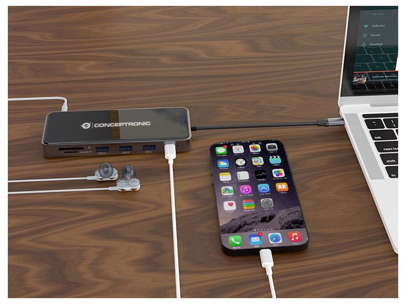 Smartphone angeschlossen an einen USB-C-Hub auf einem Schreibtisch neben einem Laptop, mit Kopfhörern und mehreren eingesteckten Kabeln.