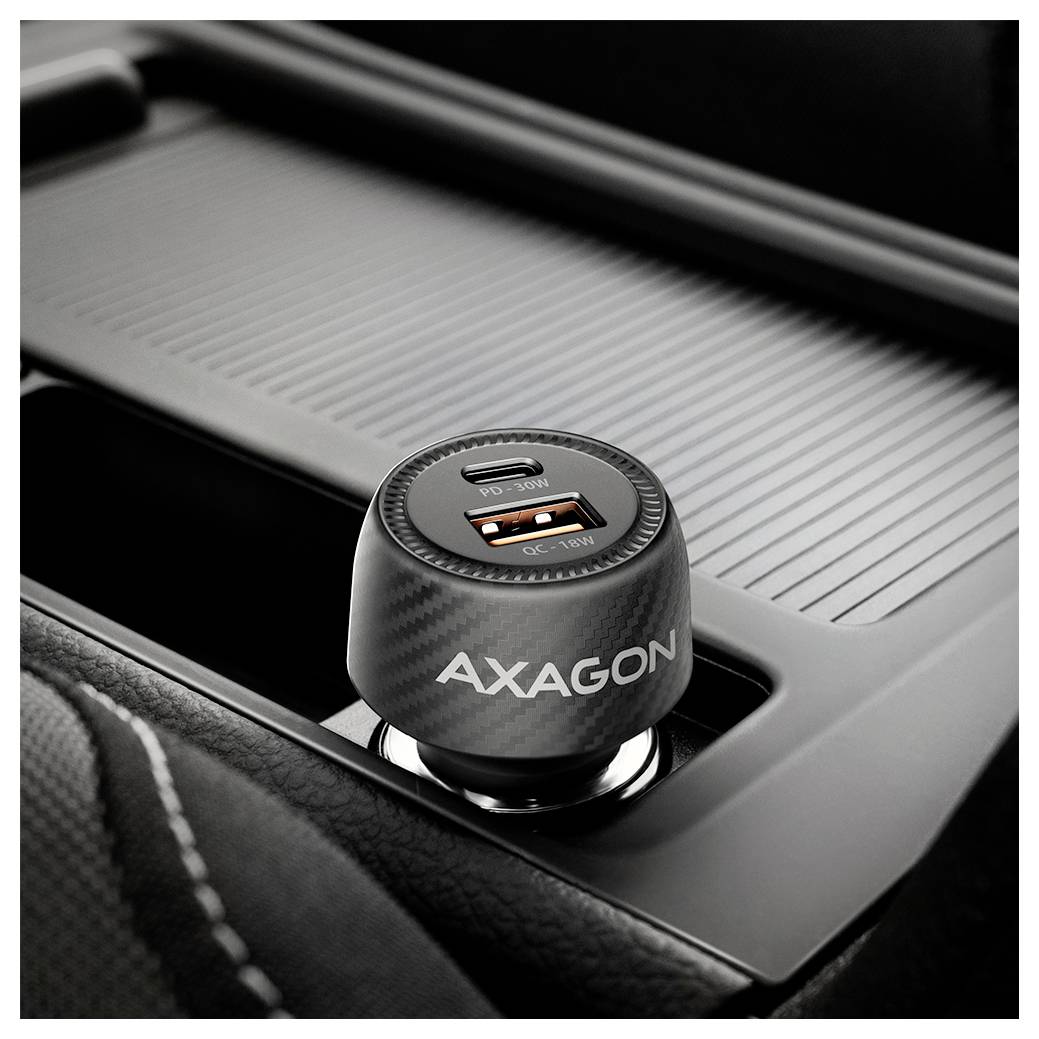 Nahaufnahme eines AXAGON Dual-USB-Autoladegeräts mit USB-C- und USB-A-Anschlüssen, das in eine Fahrzeugkonsole eingesteckt ist.