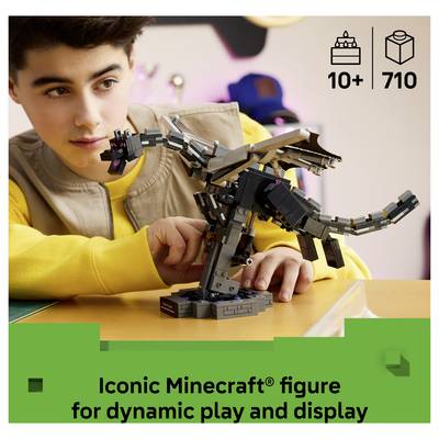 Junge stellt eine Minecraft-Drachenfigur auf einem Tisch zusammen und stellt sie aus, mit Text, der lautet „Ikonische Minecraft-Figur für dynamisches Spielen und Ausstellen" und „10+ 710".