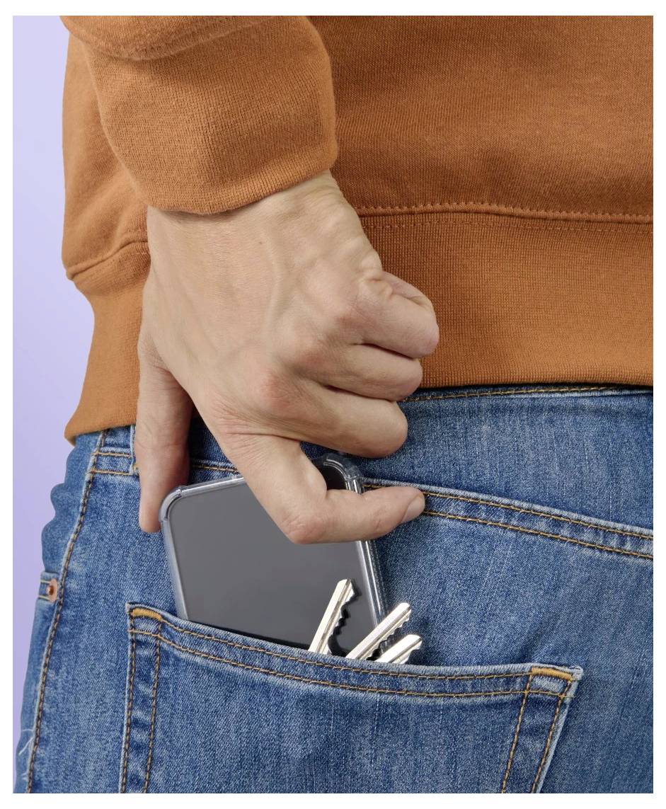 Hand, die ein Smartphone und Autoschlüssel in die Gesäßtasche einer blauen Jeans gleiten lässt.