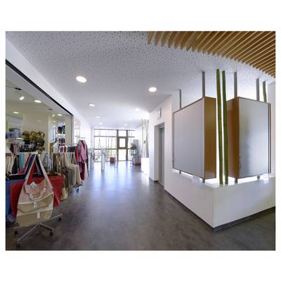 Helles Geschäft für Bekleidung im Inneren mit Kleiderstangen und Handtaschen auf der linken Seite, offener Gehweg und an der Wand montierte Display-Panels auf der rechten Seite.