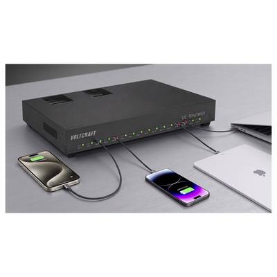 Voltcraft UC-2040WOT Ladehub auf einem Schreibtisch, mit mehreren USB-Kabeln, die zwei Smartphones und einen Laptop in der Nähe aufladen.