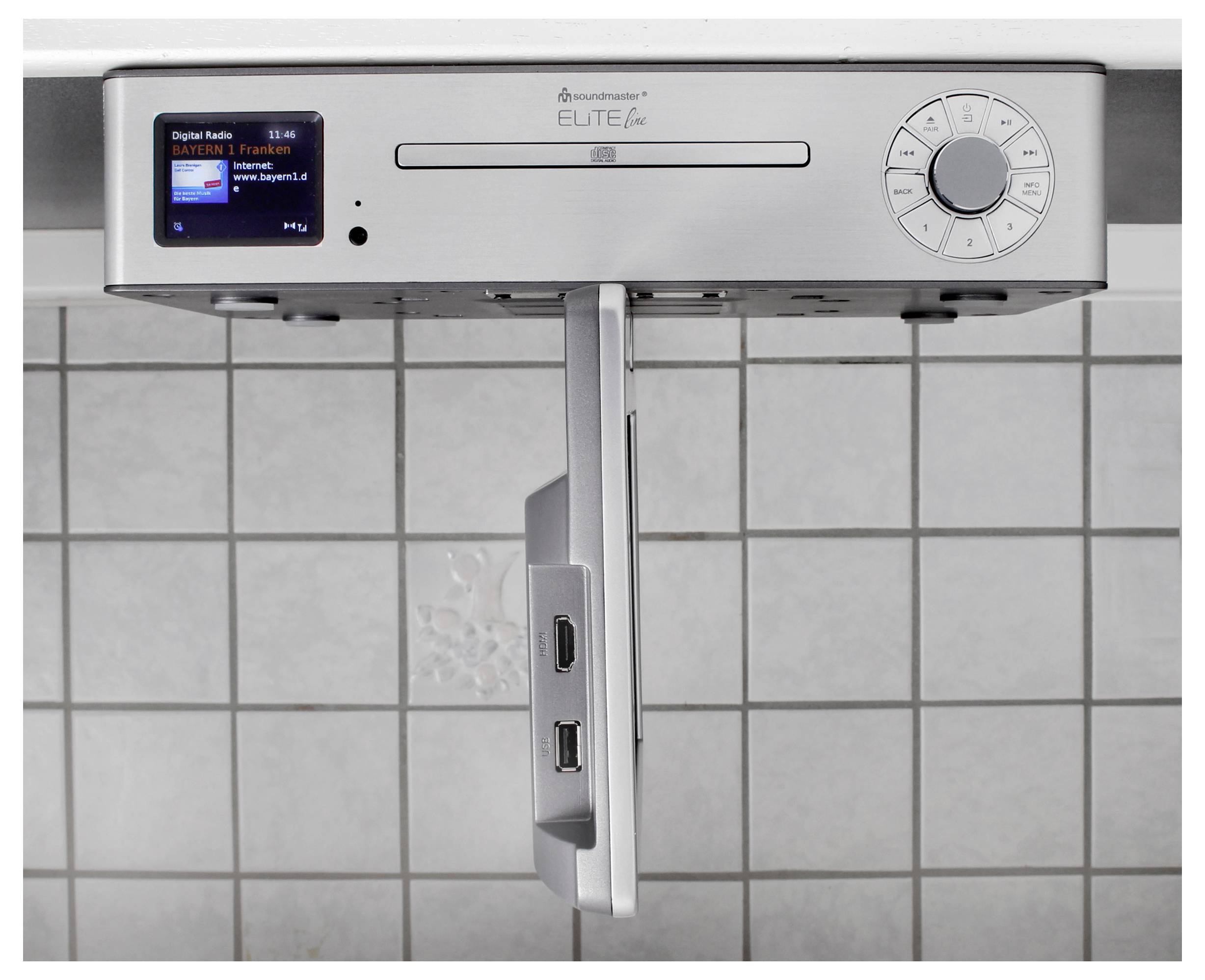 Edelstahl-Deckenheizer für das Badezimmer mit digitaler Radioanzeige, Bedienelemente und einer zentralen Ausziehstange gegen eine geflieste Wand.