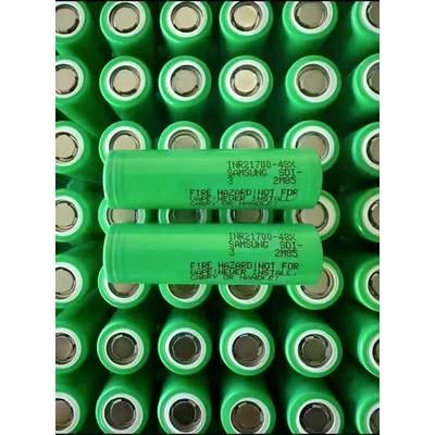 Nahaufnahme von grünen wiederaufladbaren Samsung INR21700-48G-Batteriezellen, die in Reihen angeordnet sind, mit zwei Batterien, die horizontal über vielen aufrecht stehenden Zellen liegen.