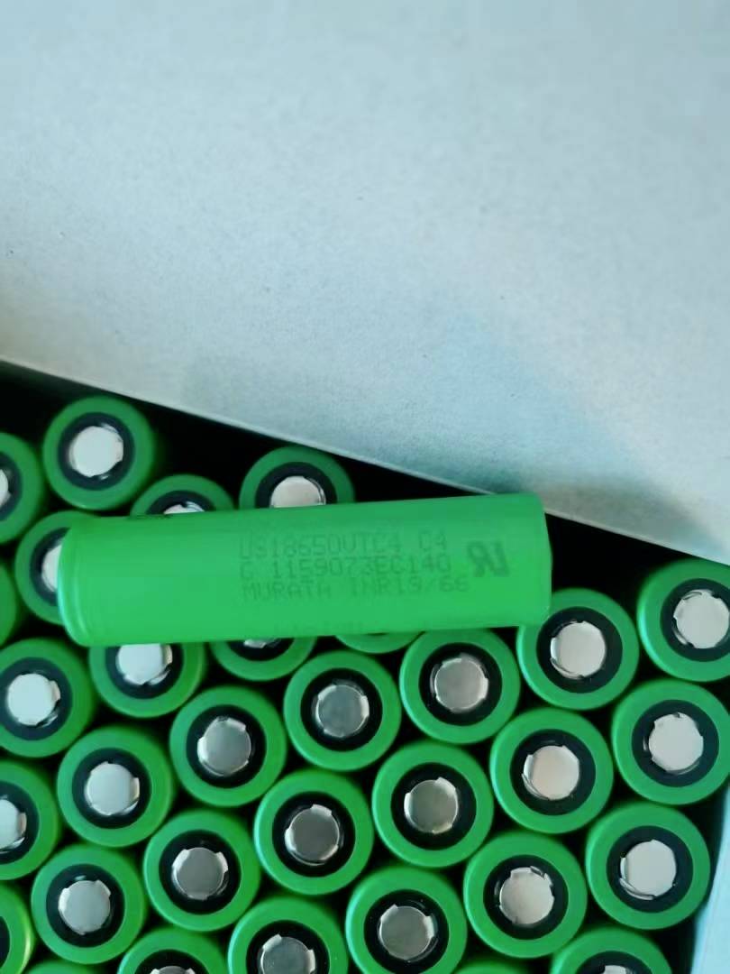 Eine grüne zylindrische Batterie liegt oben auf einer Ansammlung von grünen Batteriezellen in einer Box.