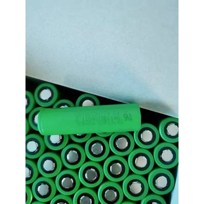 Eine grüne zylindrische Batterie liegt oben auf einer Ansammlung von grünen Batteriezellen in einer Box.