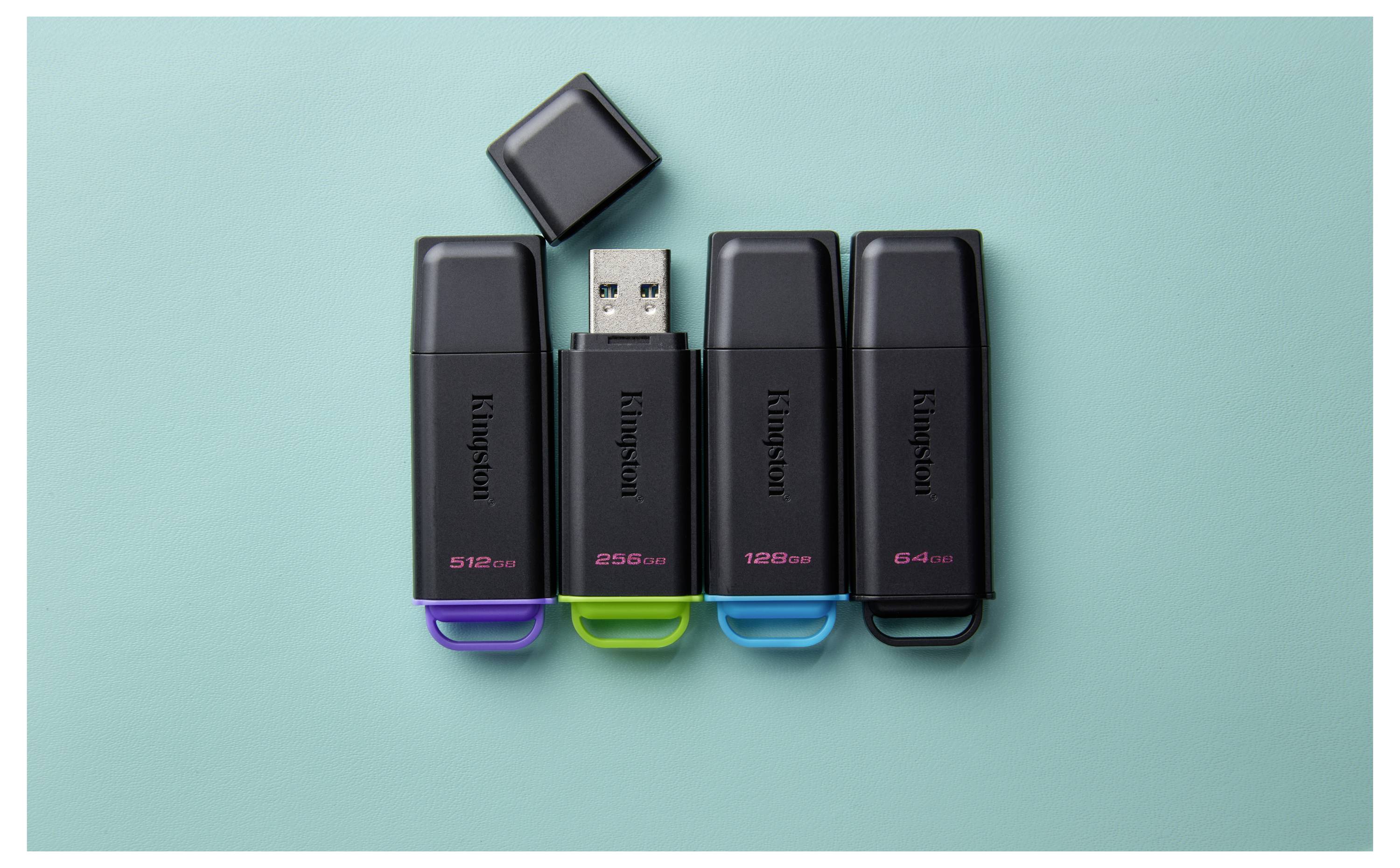 Vier Kingston USB-Speichersticks mit farbigen Kappen sind auf einem blaugrünen Hintergrund angeordnet, eine Kappe ist entfernt, um den USB-Anschluss zu zeigen.