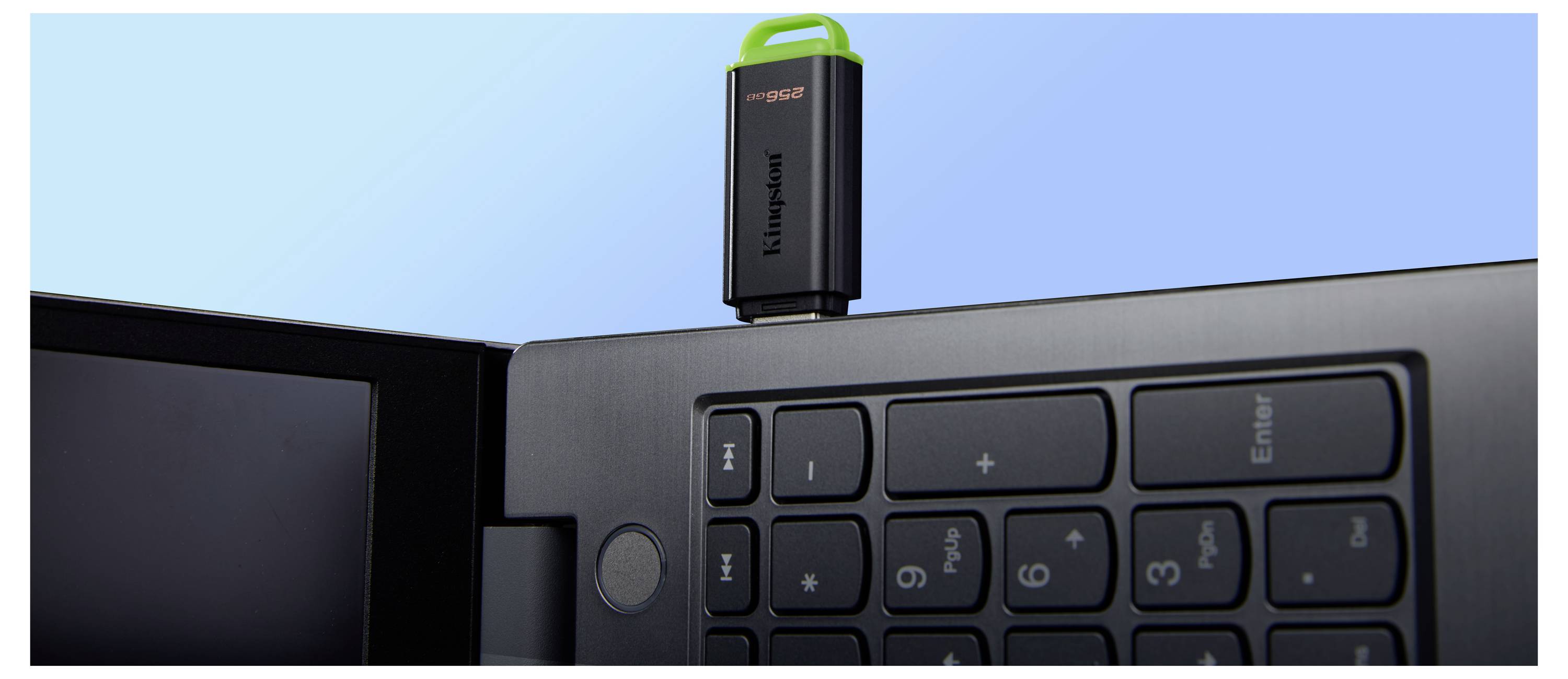 Nahaufnahme eines Laptops mit einem schwarzen USB-Dongle, der in die obere Kante über der Tastatur eingestöpselt ist.