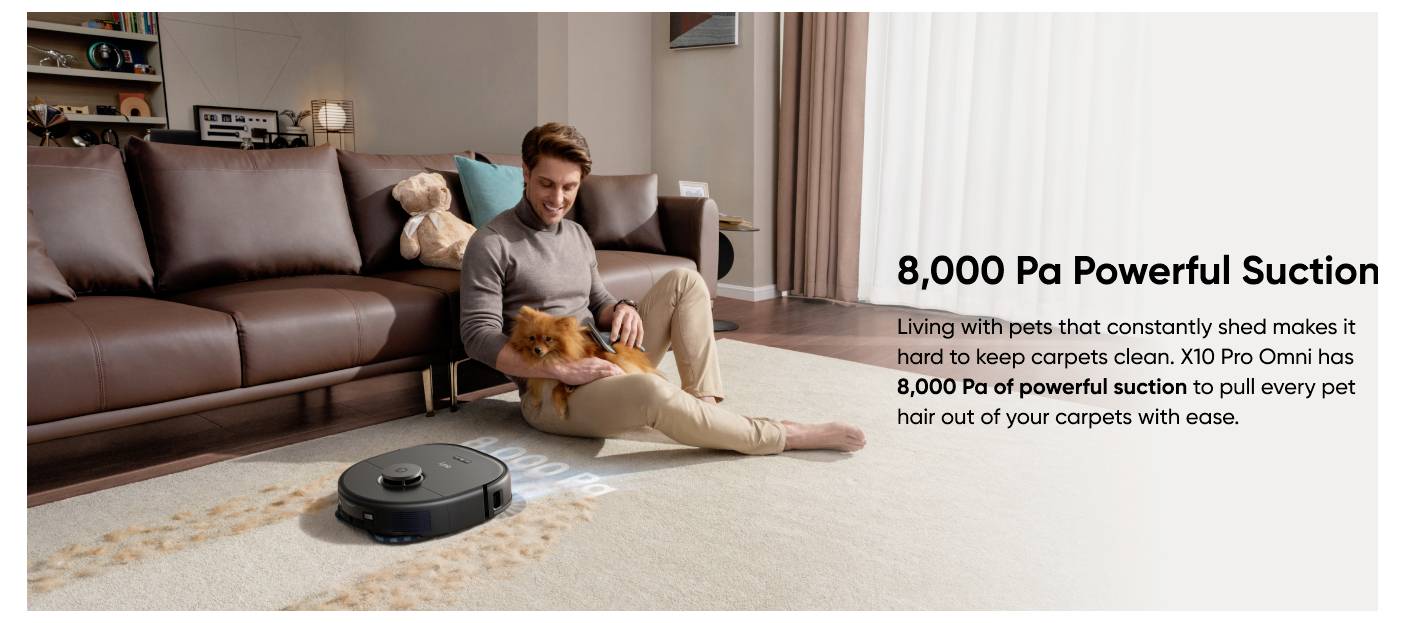 Ein Mann sitzt auf dem Boden und streichelt einen kleinen Hund, während ein Roboterstaubsauger in der Nähe reinigt; der Text hebt "8.000 Pa Powerful Suction" hervor, um Tierhaare von Teppichen zu entfernen.
