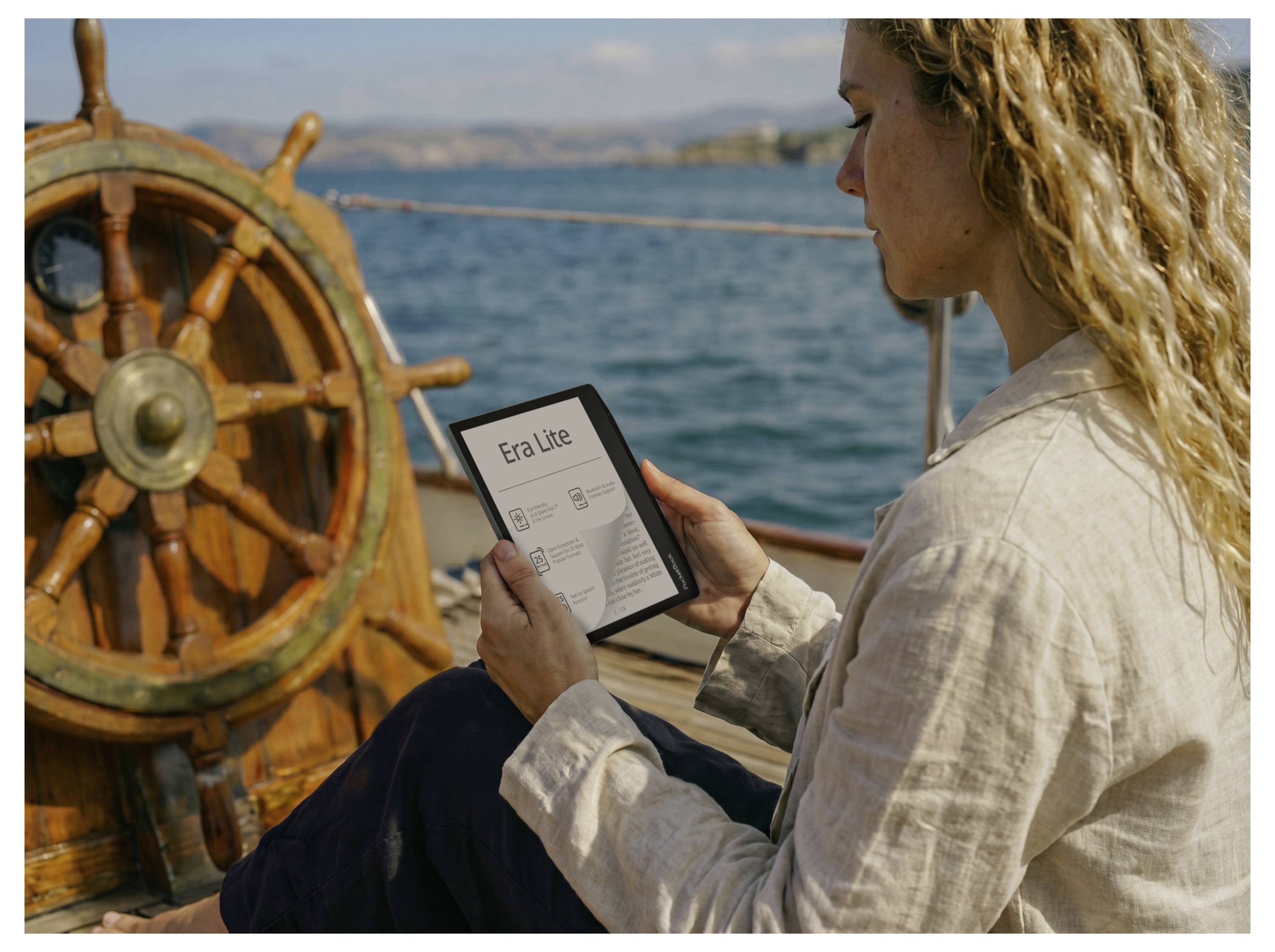 Frau auf einem Boot, die ein Tablet hält, auf dem ein Bildschirm der App „Era Lite" angezeigt wird, mit einem Schiffsrad und offenen Gewässern im Hintergrund.