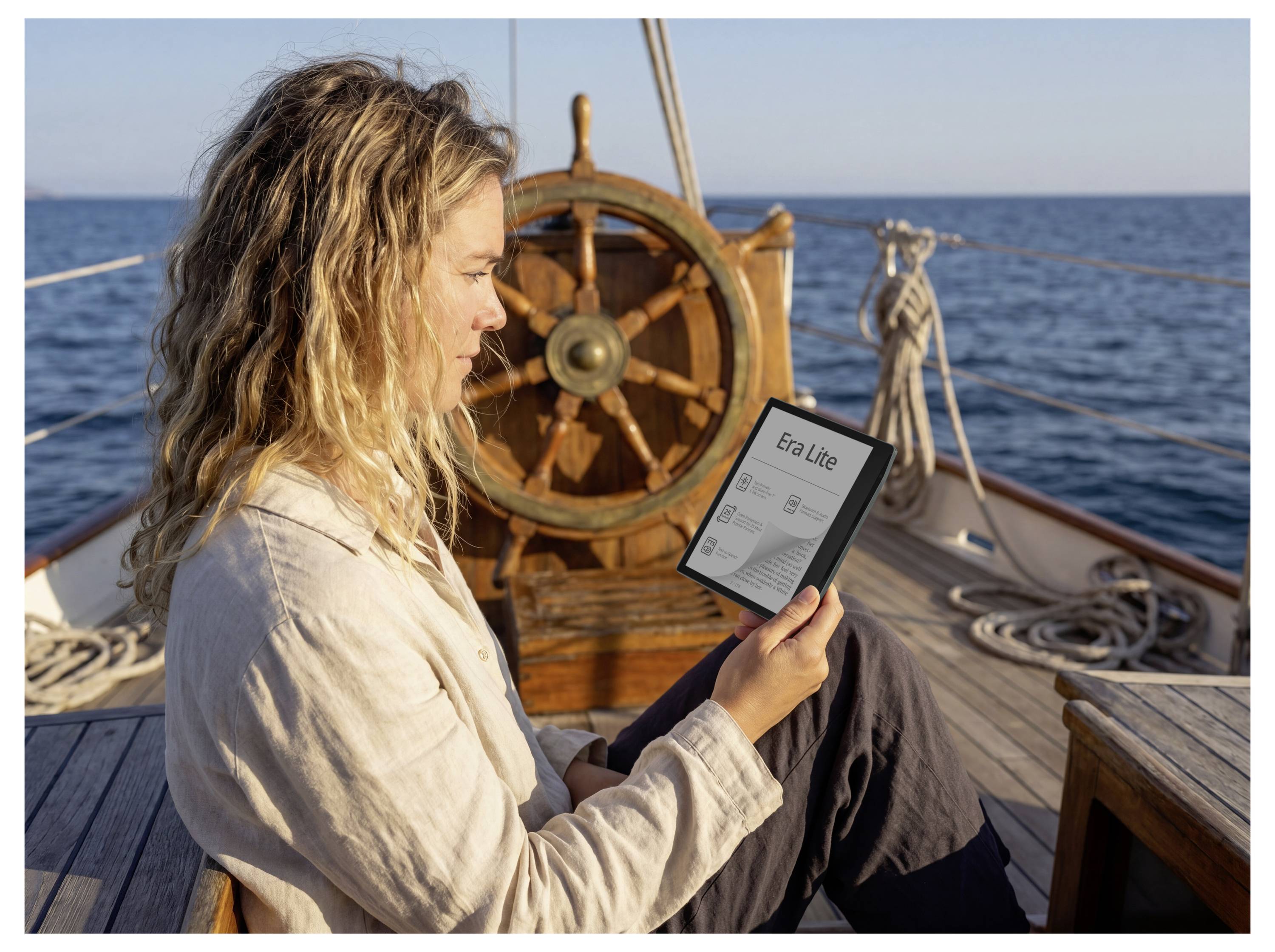 Frau auf einem Boot studiert ein Tablet mit der Anzeige "Era Lite", während sie neben dem Schiffsrad auf dem Wasser sitzt.