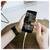 Hände halten ein Smartphone auf einem Tisch, wobei ein Finger durch eine Fotogalerie-App scrollt.