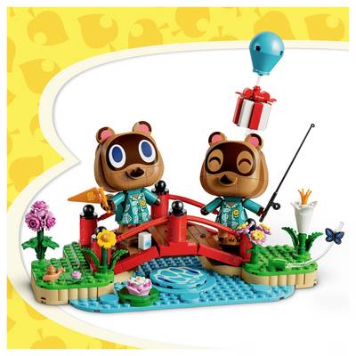 Zwei lächelnde Spielzeugbären auf einer kleinen roten Brücke über blauem Wasser, mit Blumen, einer Angelrute und einem Geschenkballon in einer verspielte LEGO-artigen Szene.