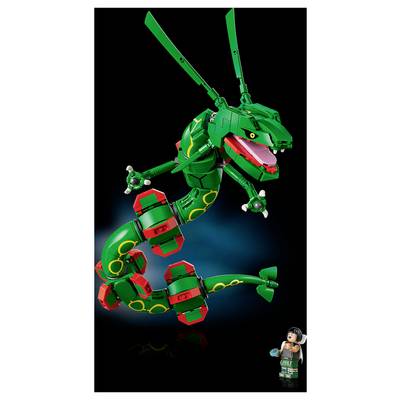 Ein grüner, roter und gelber LEGO-ähnlicher Drache springt mit offenem Maul in der Luft, neben einer kleinen Minifigur in der unteren rechten Ecke.
