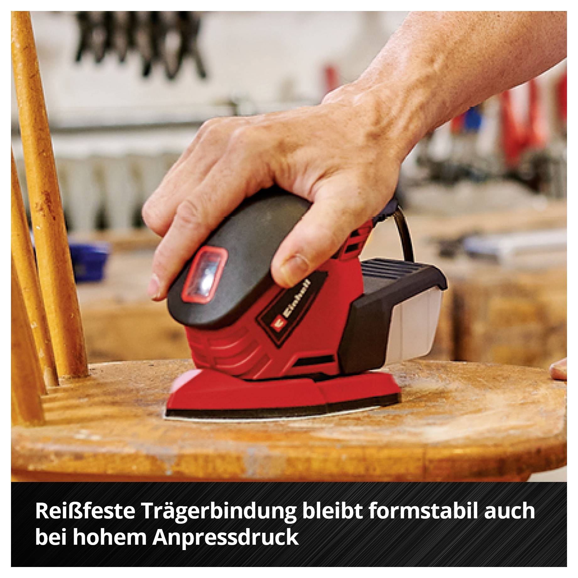 Hand schleift mit einem roten Akku-Schwingschleifer eine Holzfläche; darunter steht: 'Reißfeste Trägerbindung bleibt formstabil auch bei hohem Anpressdruck'.