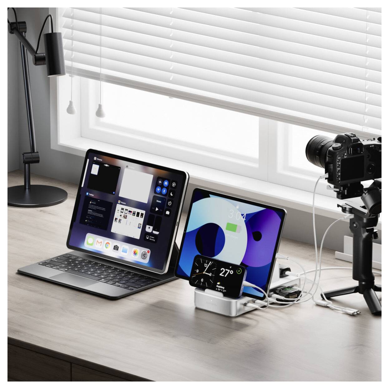 Arbeitsplatz mit zwei Tablets, einer Kamera auf einem Stativ, einer Lampe und Kabeln neben einem Fenster mit Jalousien, was auf einen Content-Creation-Arbeitsplatz hindeutet.