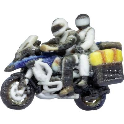Zwei Fahrer auf einem Motorrad, einer fährt und einer sitzt hinten, beide tragen Helme; eine gelbe Reisetasche ist befestigt.