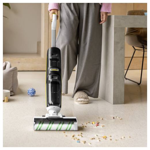 Person, die mit einem kabellosen Stabstaubsauger Krümel von einem beigen Boden in einem modernen Wohnungsinterieur aufstaubsaugt.