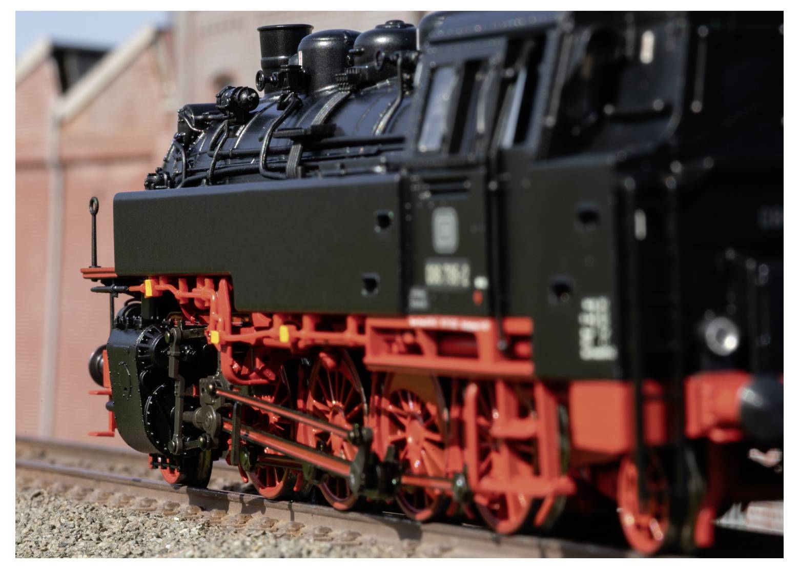 Schwarze Dampflokomotive, die grüne Personenwagen durch eine ländliche Landschaft zieht, mit Rauch, der dahinter aufwirbelt.
