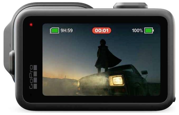 GoPro-Actionkamera zeigt eine Silhouette einer Person, die bei Sonnenuntergang auf einem Fahrzeug steht, mit Aufnahme- und Batterieindikatoren auf dem Bildschirm.