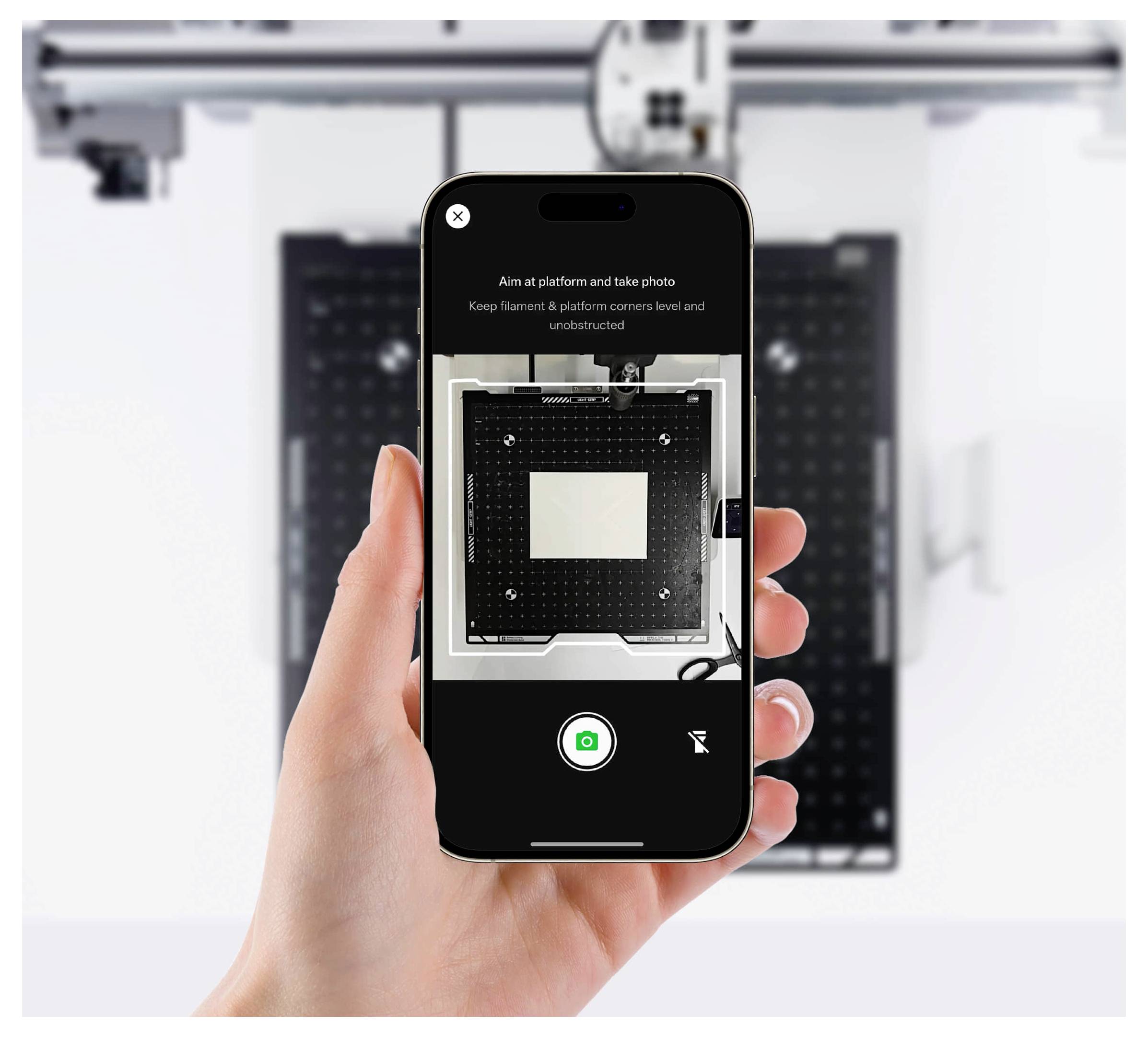 Hand hält ein Smartphone mit Kameraansicht mit Anweisungen, auf die Plattform zu zielen und ein Foto zu machen, mit einem schwarzen Gerät auf weißem Hintergrund im Bild.