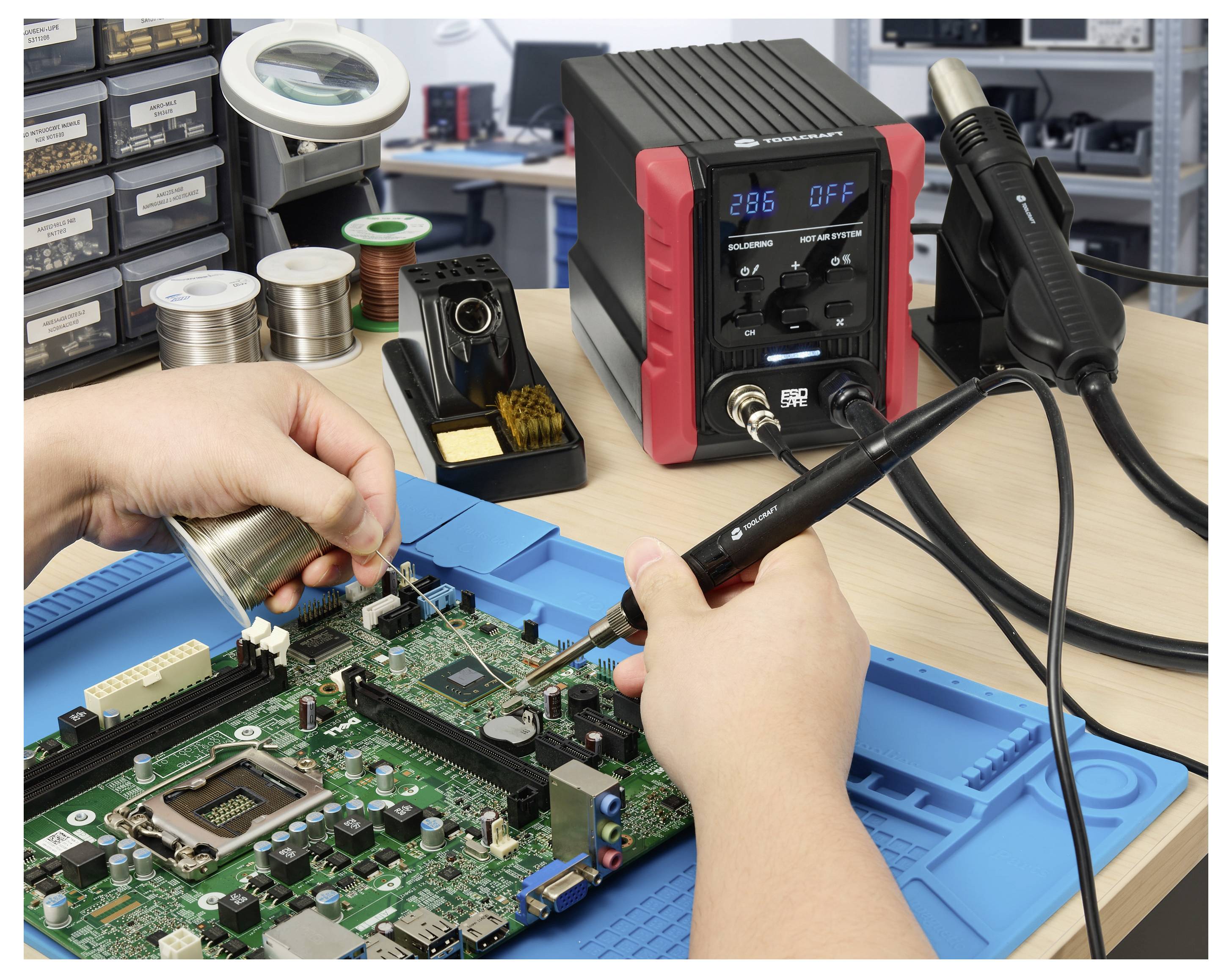 Hände löten eine Leiterplatte auf einer blauen Reparaturmatte, mit einer Lötstation und Werkzeugen auf der Werkbank in einer Elektronikwerkstatt.