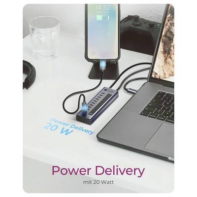 Telefon wird über einen USB-C-Hub neben einem Laptop aufgeladen, wobei der Text „Power Delivery 20 W" und „Power Delivery mit 20 Watt" auf dem Schreibtisch hervorgehoben wird.