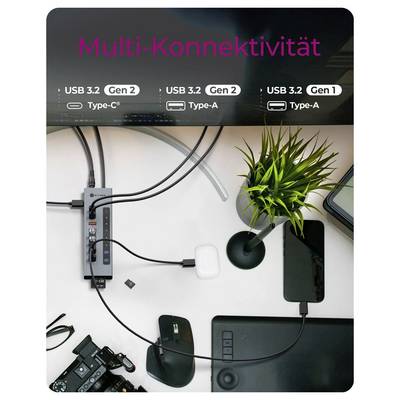Draufsicht eines Schreibtischs mit einer USB-C-Dockingstation mit der Bezeichnung „Multi-Konnektivität", die einen Laptop, ein Telefon, eine Maus, eine Kamera und Peripheriegeräte über USB 3.2 Gen 1/2-Anschlüsse verbindet.
