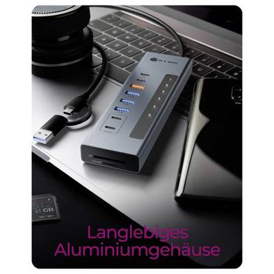 Nahaufnahme eines USB-C-Hubs/einer Dockingstation auf einer Laptop-Tastatur mit mehreren Anschlüssen und einem Telefon in der Nähe; der Text lautet „Langlebiges Aluminiumgehäuse".