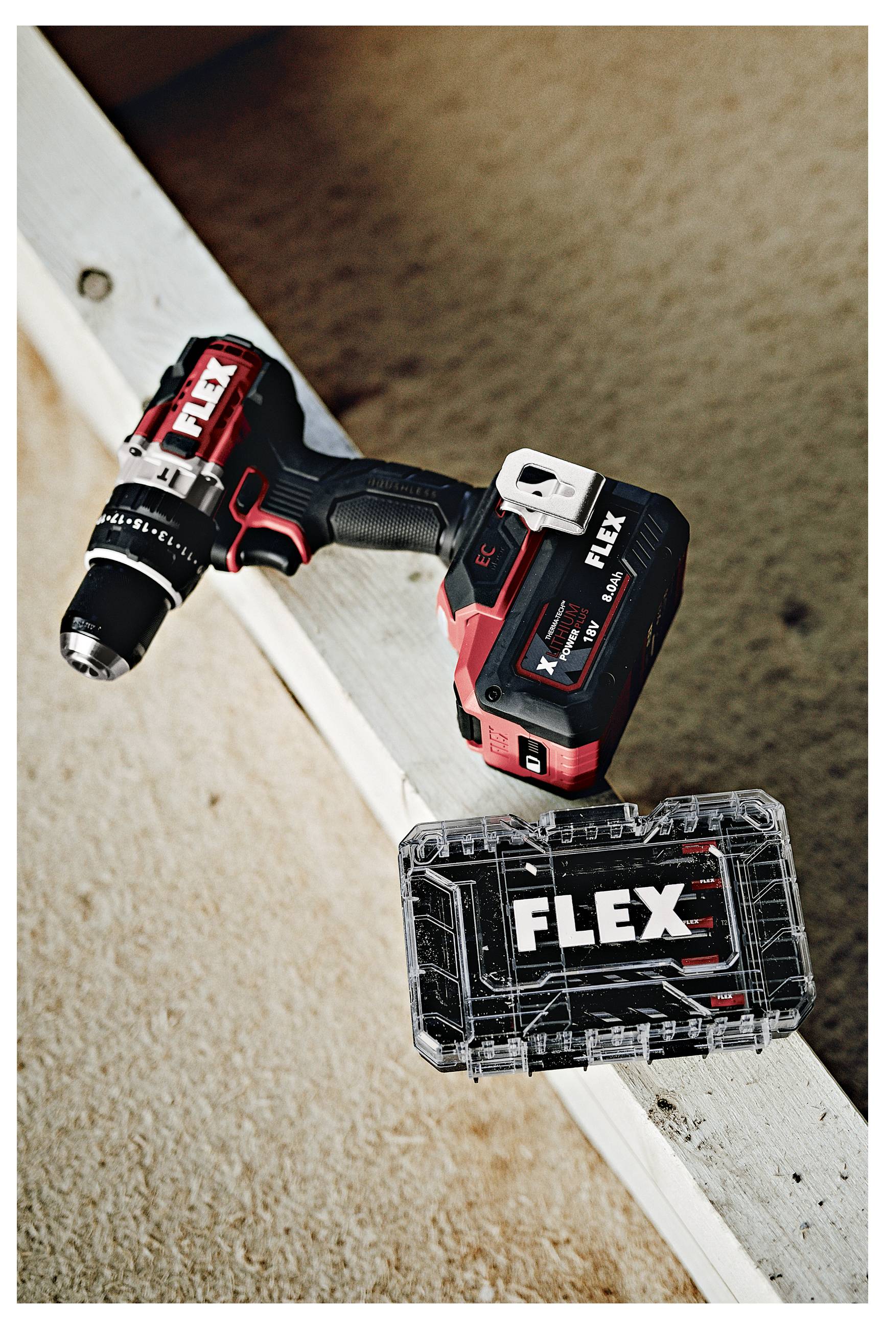 Schnurloses FLEX-Elektrowerkzeug mit Batteriepack, das auf einer weißen Holzkante ruht, in Nahaufnahme vor einem beigen Boden gezeigt.