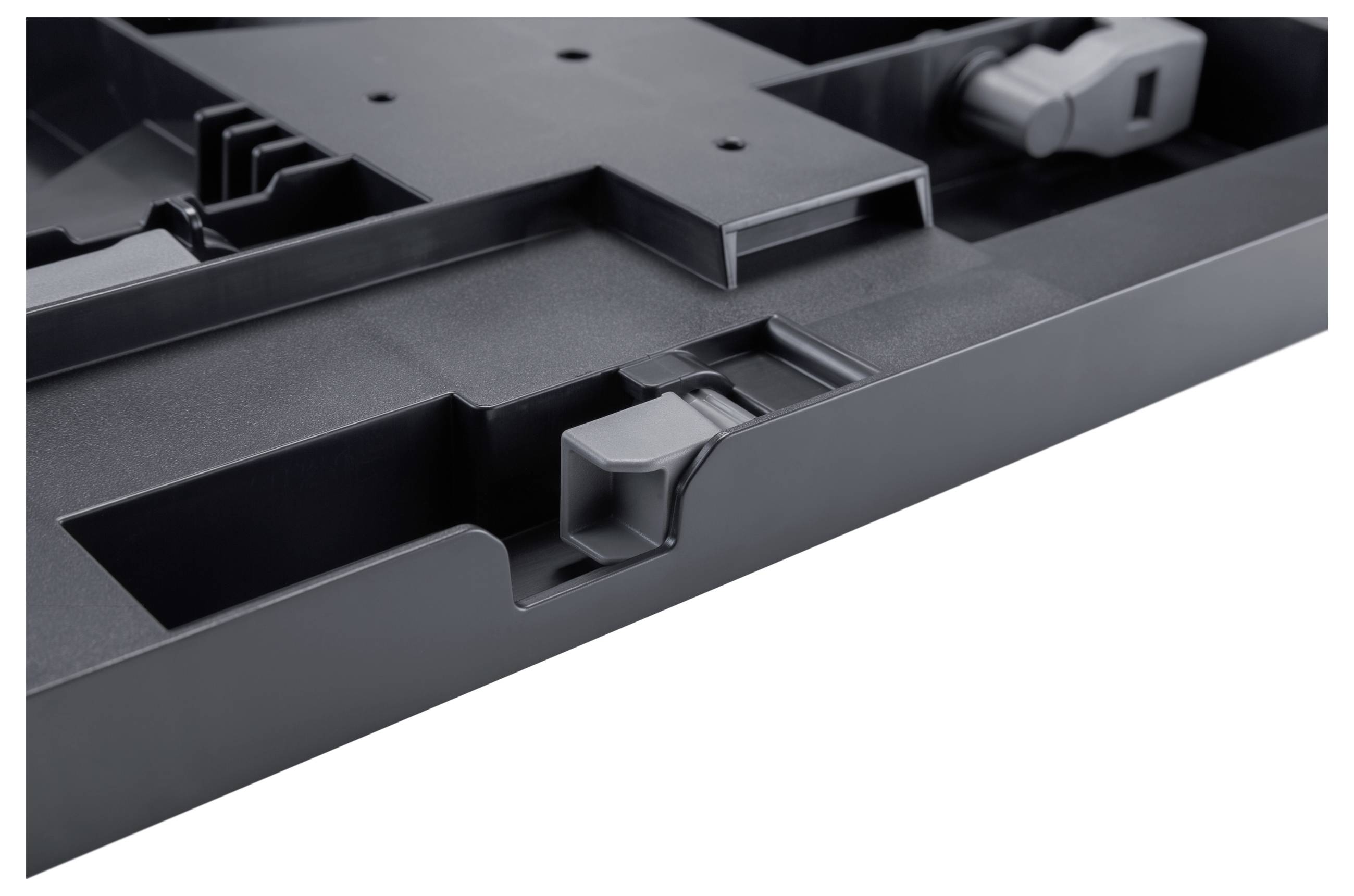 Nahaufnahme des Inneren eines schwarzen kunststoffgebundenen elektronischen Geräts mit geformten Schlitzen, Clips und Befestigungselementen.