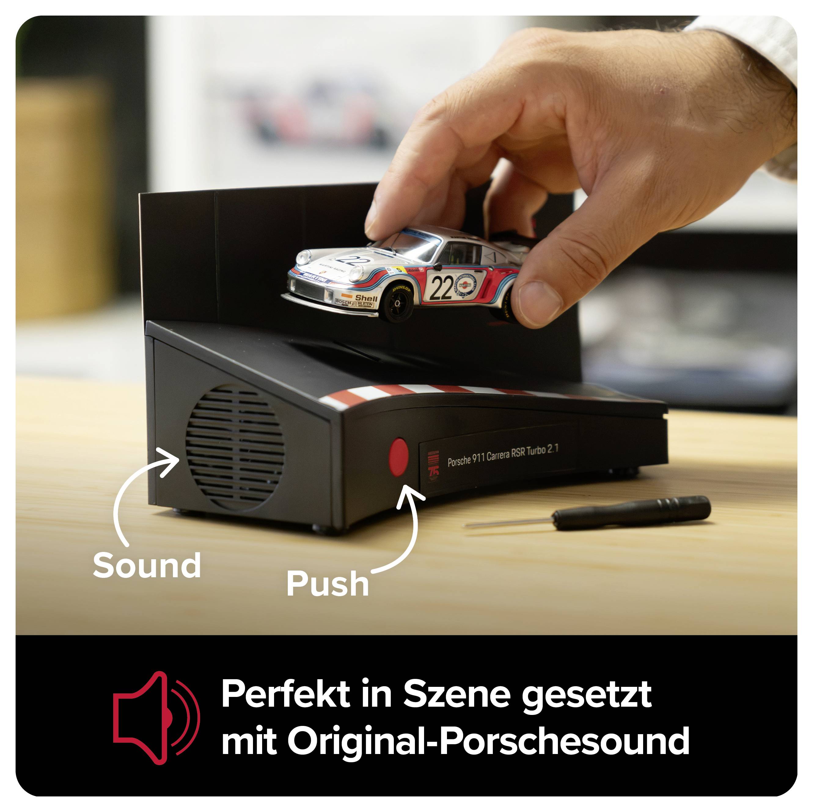 Hand platziert ein Porsche-Modell auf einem Soundgerät; Pfeile mit 'Sound' und 'Push', darunter der Text 'Perfekt in Szene gesetzt mit Original-Porschesound'.