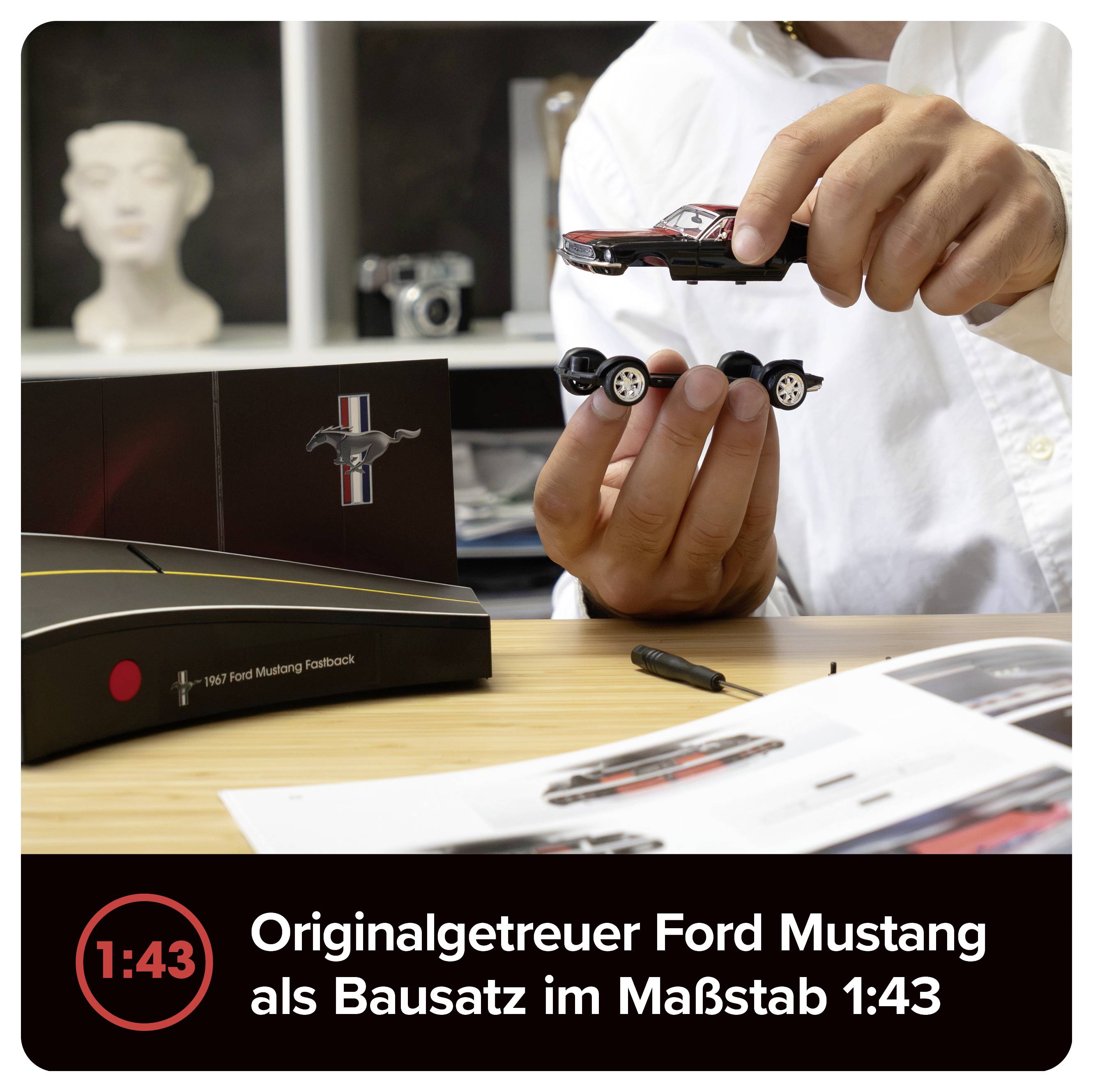 Person hält einen Ford Mustang Modellbausatz im Maßstab 1:43; Produktverpackung und Titel 'Originalgetreuer Ford Mustang als Bausatz im Maßstab 1:43' sind sichtbar.