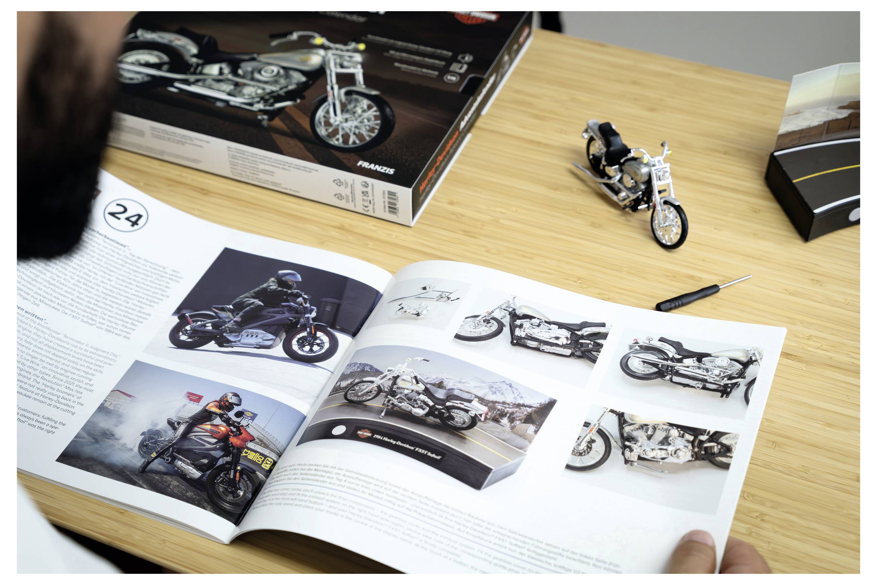 Öffnen Sie einen Motorradkatalog auf einem Holzschreibtisch mit einem kleinen Modellmotorrad und einer Motorradproduktbox in der Nähe.
