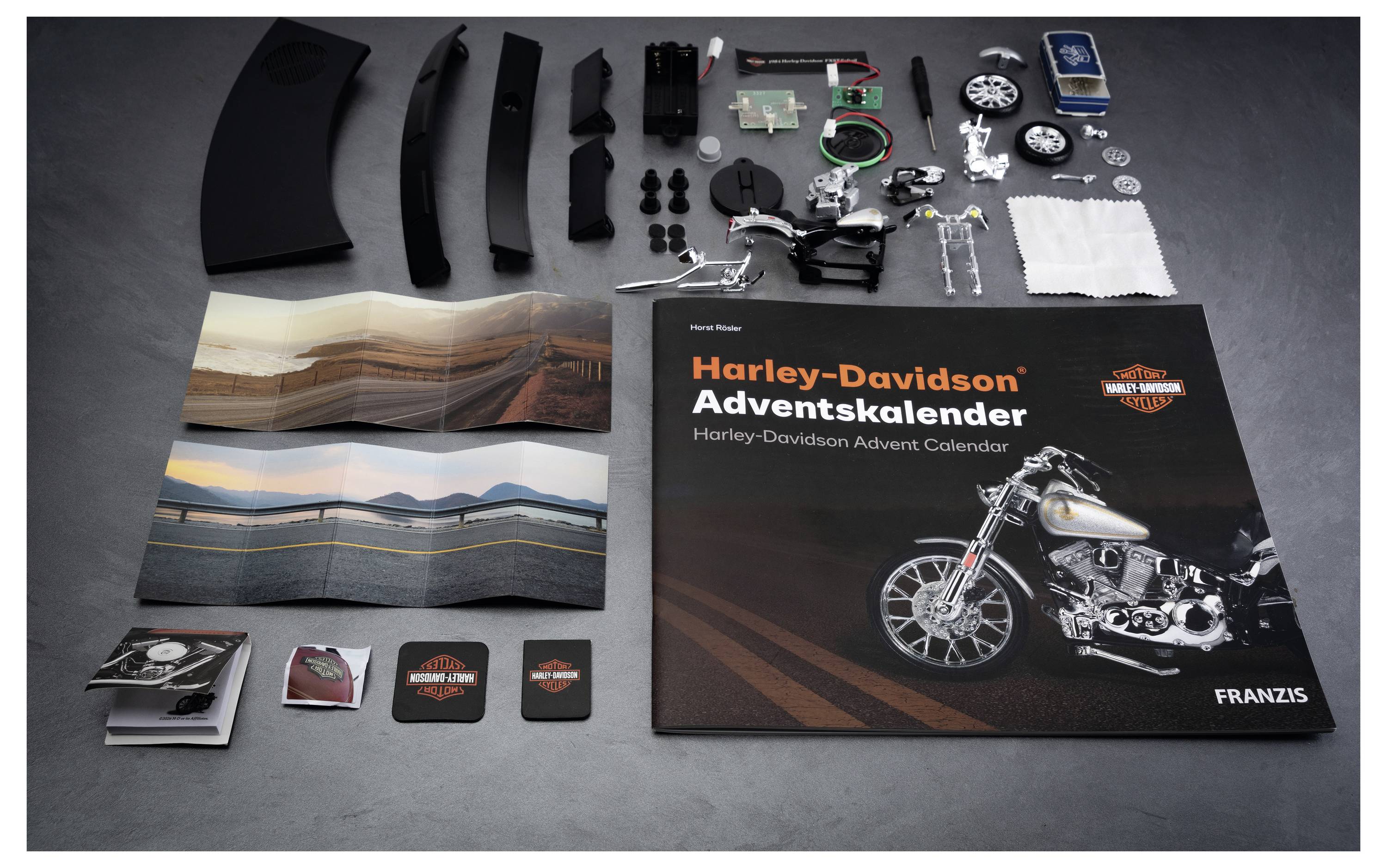 Harley-Davidson Adventskalender-Set mit ausgelegten schwarzen Kunststoffteilen, kleinen Zubehörteilen, gedruckter Anleitung und Kalenderbox mit Motorradabbildung.